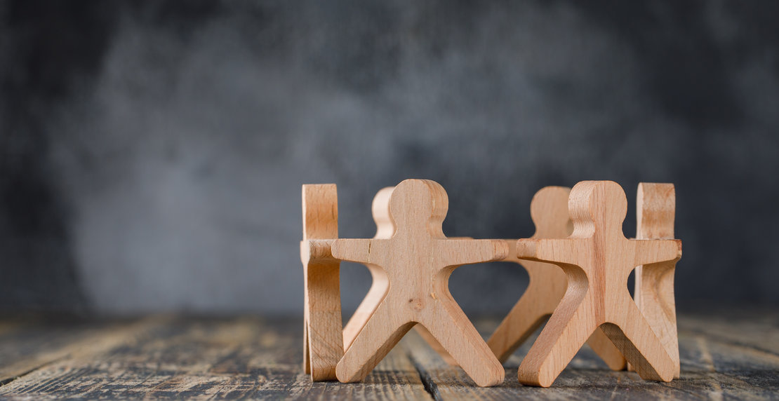 Business success and teamwork concept with wooden figures of people on wooden and foggy background side view.