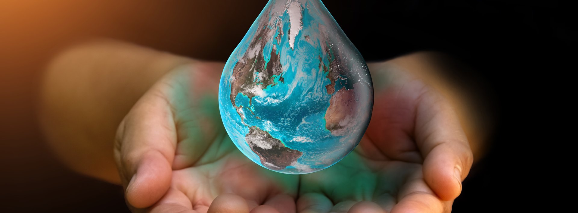 Blue Earth world with dripping water on two hand at wait on abstract black background. Water shortage and earth day concept or world water day.